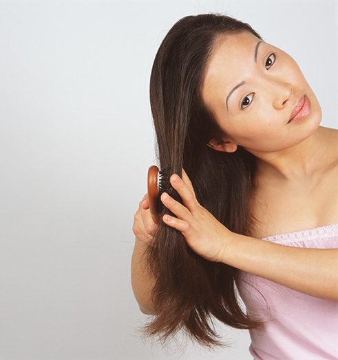 Asian woman brushing hair isolated on white background
